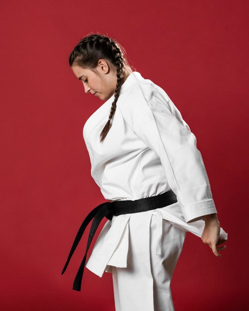 Sideways karate woman in traditional white kimono on red background