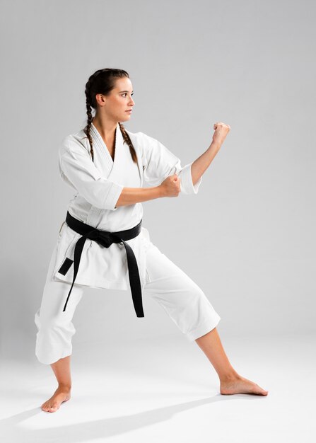 Sideways karate woman in traditional white kimono on white background
