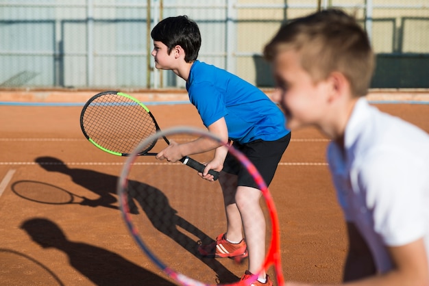 sideways kids playing doubles tennis