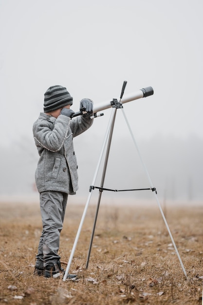 Sideways little boy using a telescope