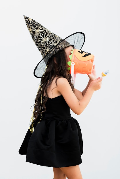 Бесплатное фото Боком маленькая девочка в костюме ведьмы на хэллоуин