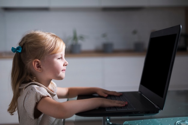 Sideways little girl playing on laptop