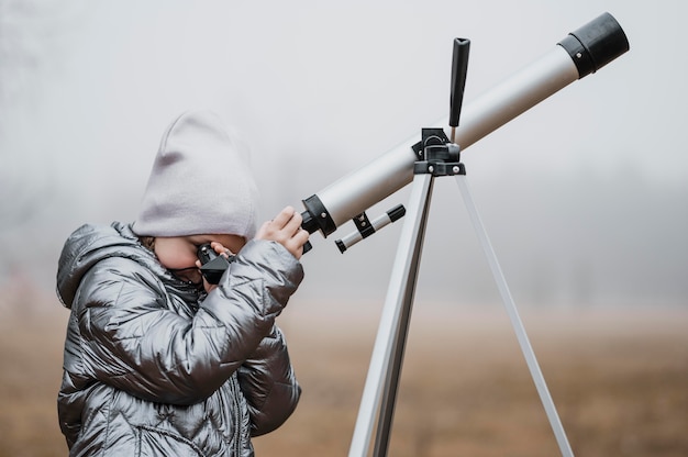 Sideways little girl using a telescope