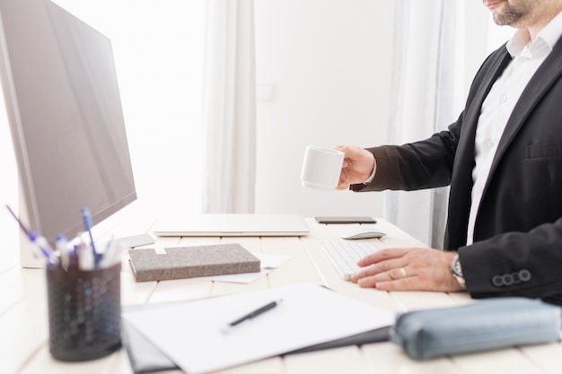 Sideways man having a cup of coffee at his desk