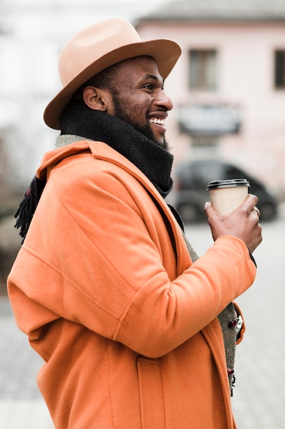 Free photo sideways man holding a paper cup of coffee