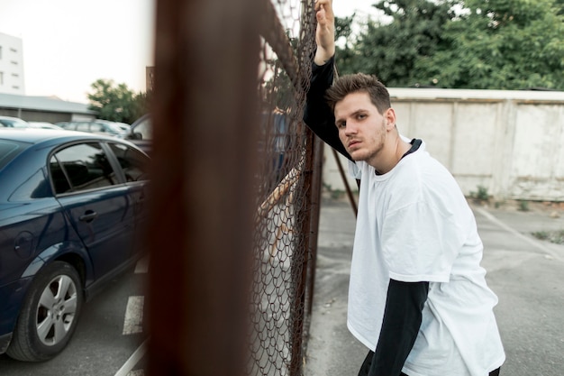 Sideways man leaning against a fence