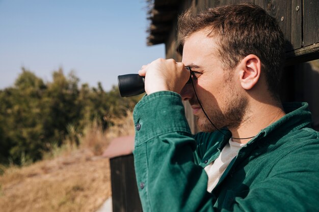 Sideways man looking through binoculars