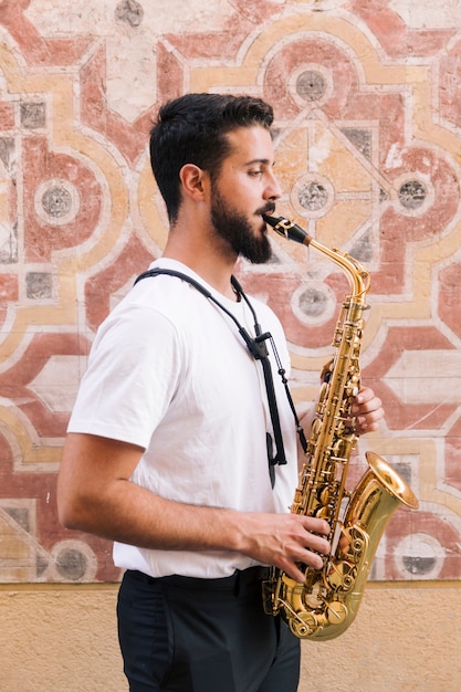 Sideways man medium shot playing the saxophone with geometric background
