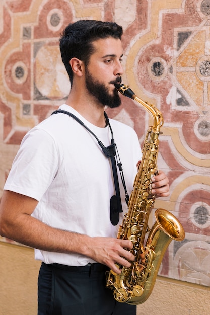 Free photo sideways man medium shot playing the saxophone with geometric background