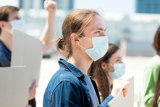 Боком человек протестует и носит медицинскую маску