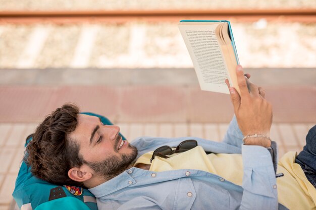Sideways man reading a book on train staion