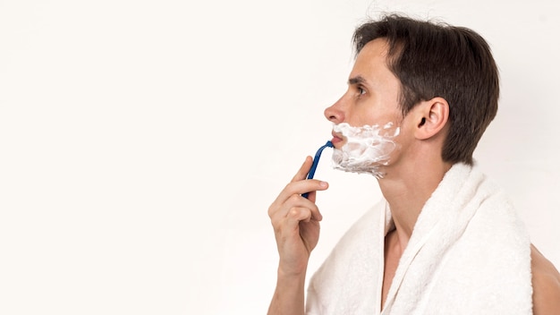 Free photo sideways man shaving with copy space