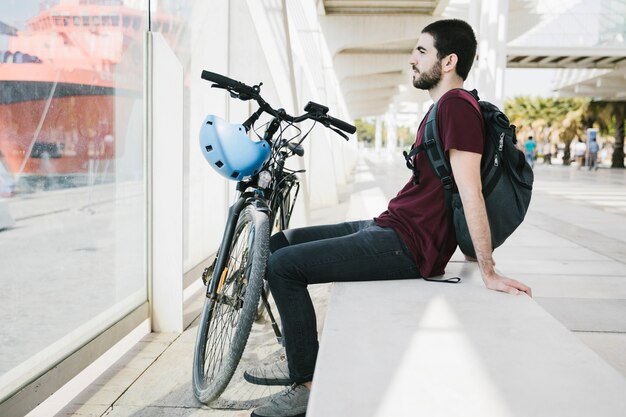 Боком человек, сидящий рядом с велосипедом