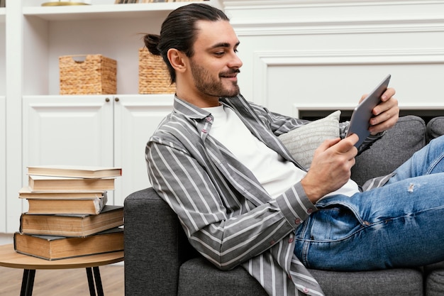 Sideways man sitting on the couch with a tablet