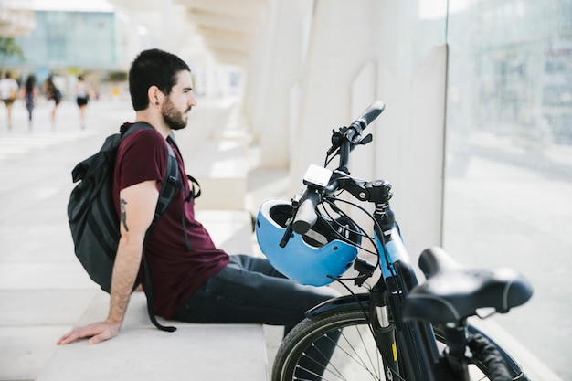 Sideways man sitting next to electric bicycle