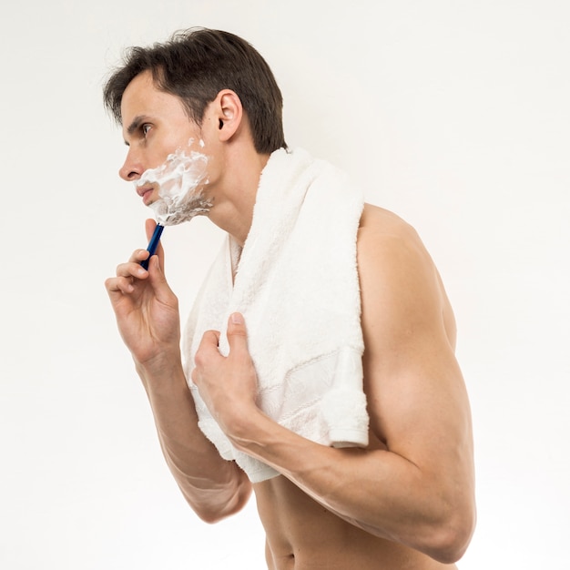 Free photo sideways of man  standing andshaving