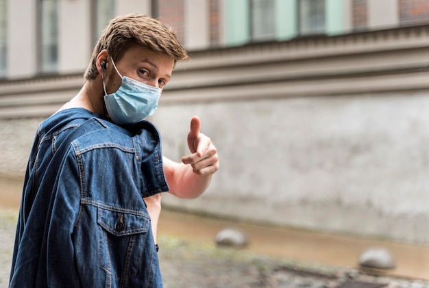 Sideways man wearing a medical mask outside with copy space