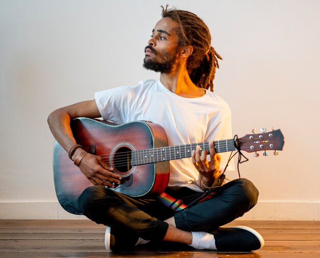 Sideways man with dreads playing the guitar