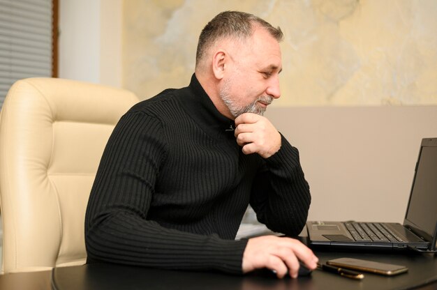 Sideways mature man working at his desk