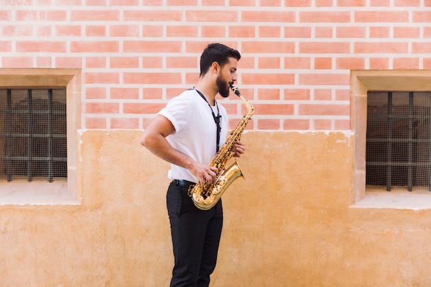 Free photo sideways medium shot man playing the saxophone