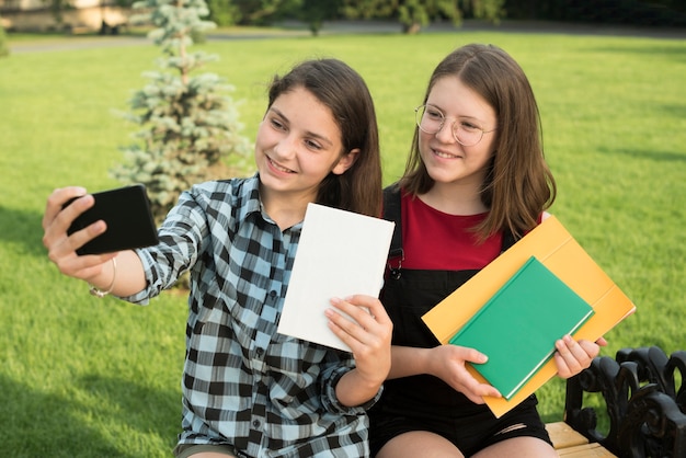 Sideways medium shot of teenage girls taking a selfie