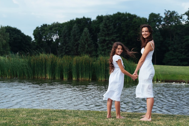Боком мать и дочь позирует на озере