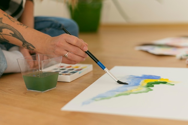 Sideways person sitting on the floor and paints