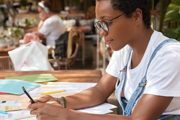 Free photo sideways shot of afro american blogger chats online, reads news on internet website