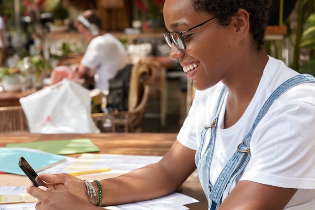 Sideways shot of cheerful hipster girl dressed in casual white t shirt