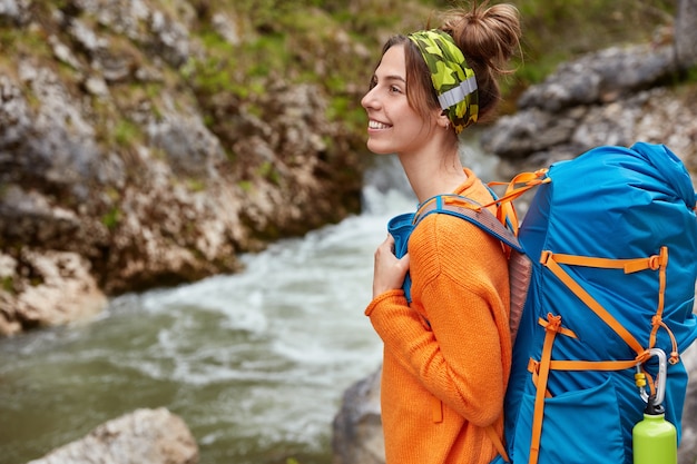 Foto gratuita inquadratura laterale di allegre passeggiate turistiche vicino al piccolo ruscello, concentrata lontano