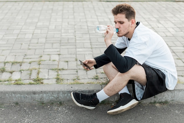 Free photo sideways sitting man hydratating