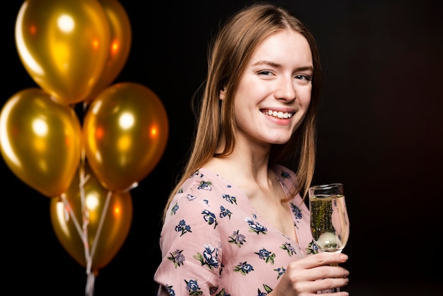 Free photo sideways smiley woman holding a glass of champagne