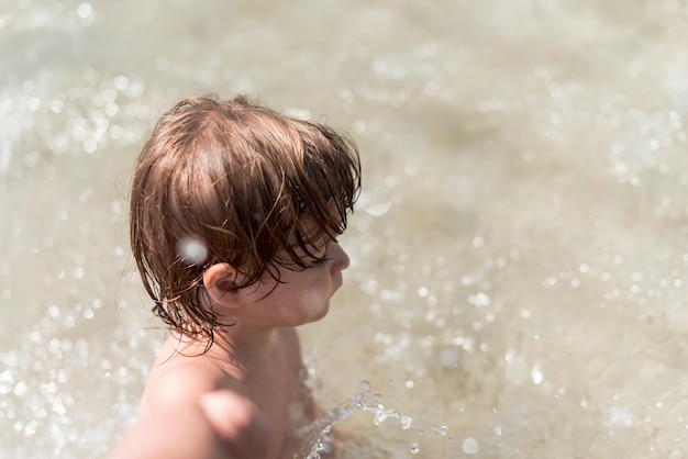 Боковой вид сверху ребенок играет в воде