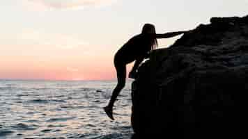 Free photo sideways woman climbing on a rock