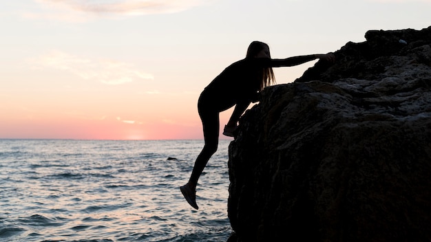 Sideways woman climbing on a rock