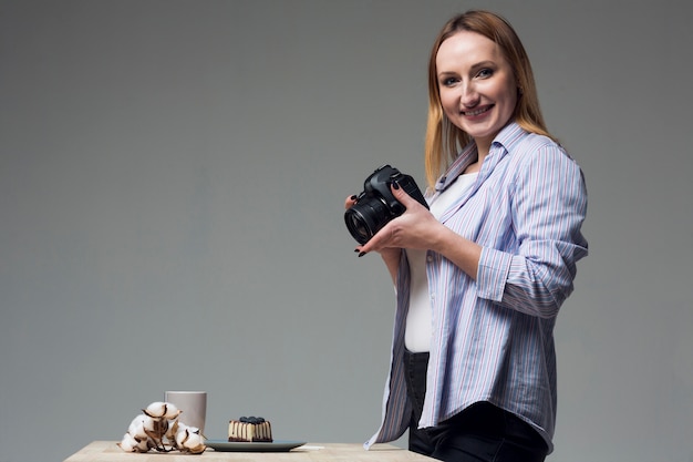 Free photo sideways woman holding a professional camera in studio