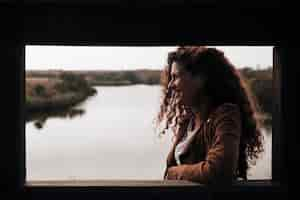 Free photo sideways woman leaning against a window ledge