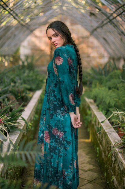 Sideways woman posing in a green house looking at camera