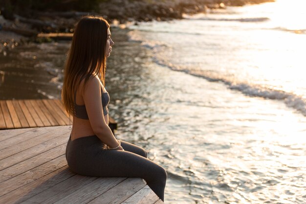 Sideways woman sitting next to the beach with copy space