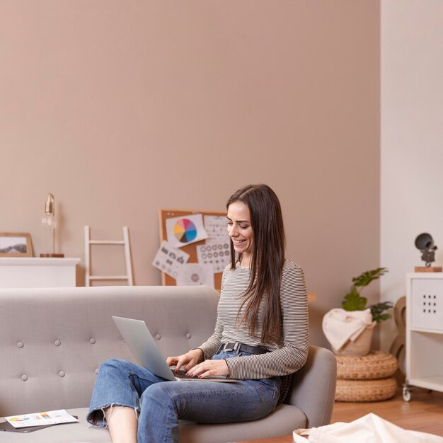 Sideways woman sitting on couch and works