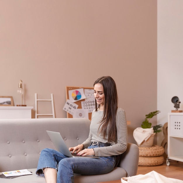 Sideways woman sitting on couch and works