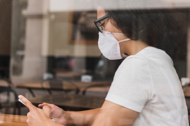 Sideways woman with medical mask checking her phone