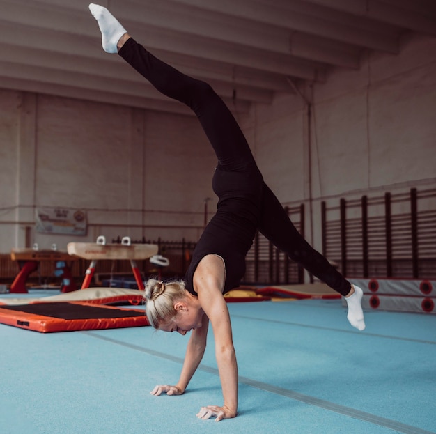 体操選手権のための横向きの若いブロンドの女性のトレーニング