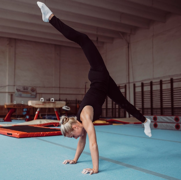 Sideways young blonde woman training for gymnastics championship