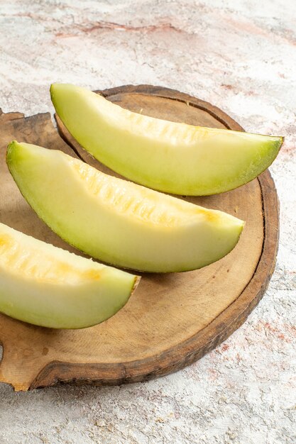 Sidewise shot of melons on wooden platter on white marble