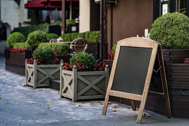 Signboard Stand Blackboard cafe Menu Shop Restaurant with Bushes in pots outdoors