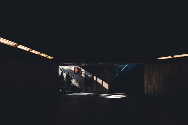 Silhoette двух человек, входящих в темное тенистое подземное здание