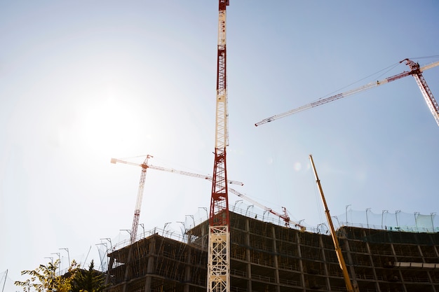 Silhouette of buildings under construction against blue sky in sunlight