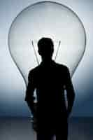 Free photo silhouette of businessmen with a lightbulb background