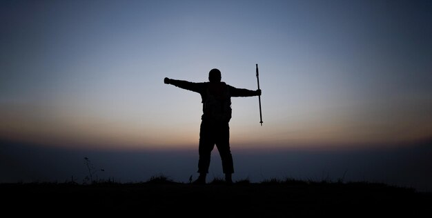Silhouette of cheering hiking man open arms to the sunrise stand on mountain Travel Lifestyle wanderlust adventure concept summer vacations outdoor